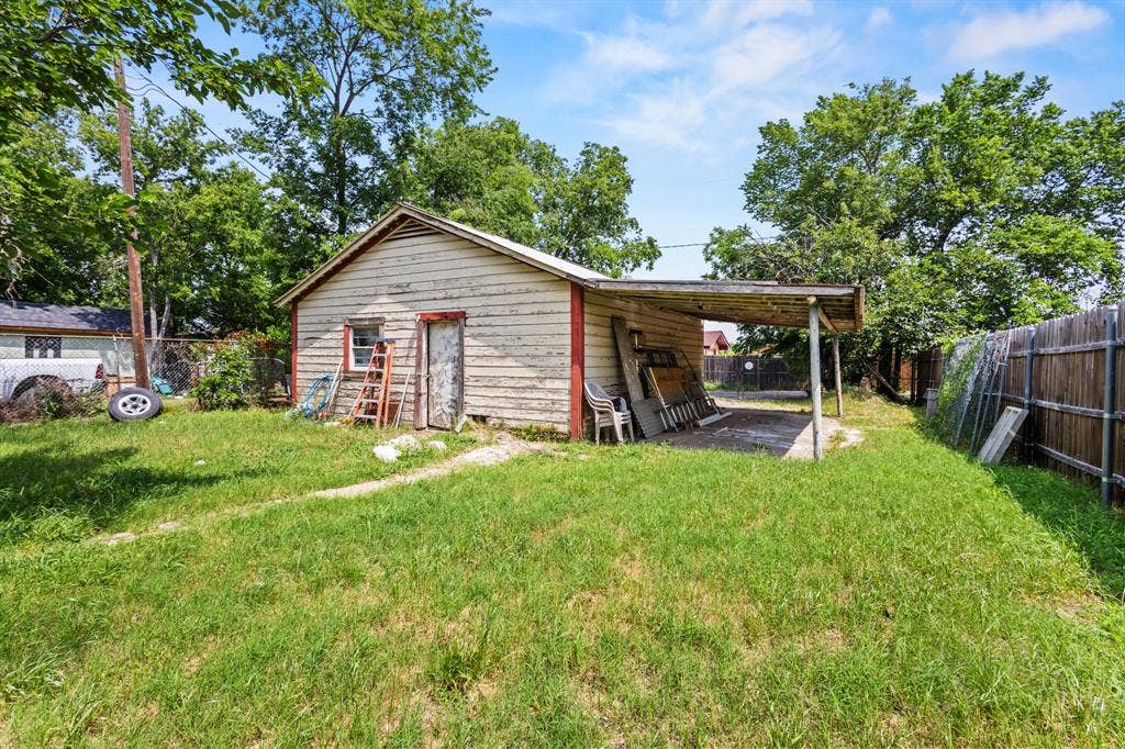 2006 Fort Worth Street, Grand Prairie, TX 75050 Detached outbuilding with an attached carport, featuring wood siding and a gabled roof