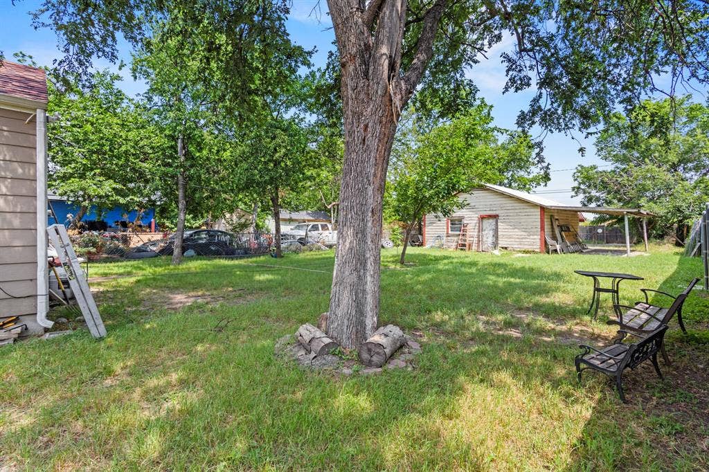 2006 Fort Worth Street, Grand Prairie, TX 75050 Expansive green space featuring a mature shade tree and a detached outbuilding with an attached covered porch