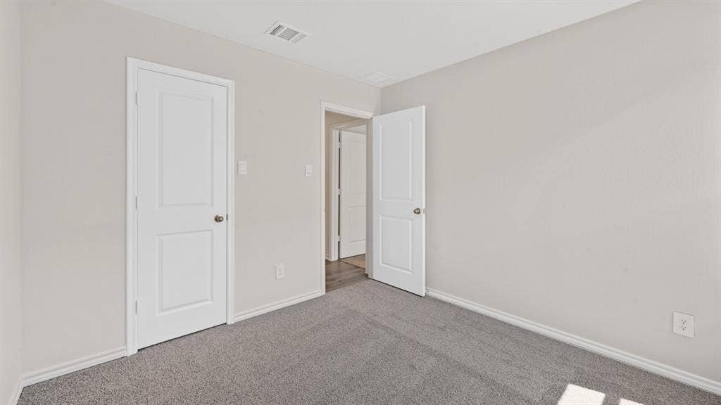 1631 Blaire Drive, Tyler, TX 75702 Interior room featuring light gray walls, gray carpet, white baseboards, and white paneled doors with brushed nickel hardware