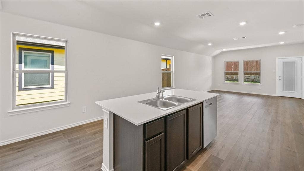 1631 Blaire Drive, Tyler, TX 75702 Kitchen island with an undermount double-basin stainless steel sink, solid surface countertop, and dark wood cabinetry
