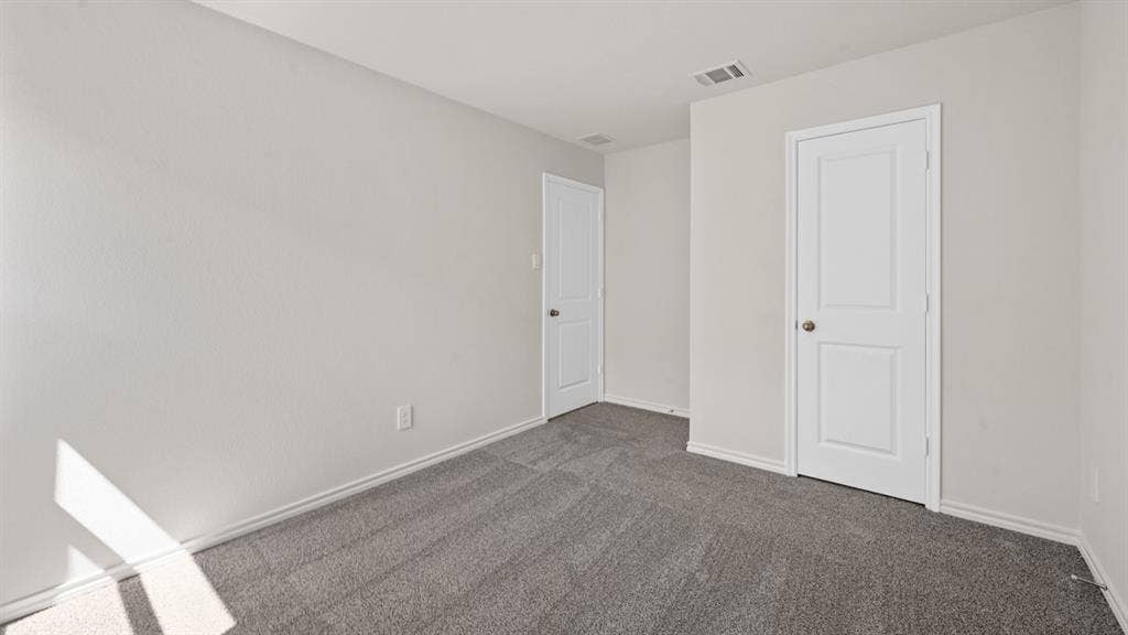 1631 Blaire Drive, Tyler, TX 75702 Neutral-toned walls complement the gray carpeting in this room, featuring two white two-panel doors with round knobs and white baseboards