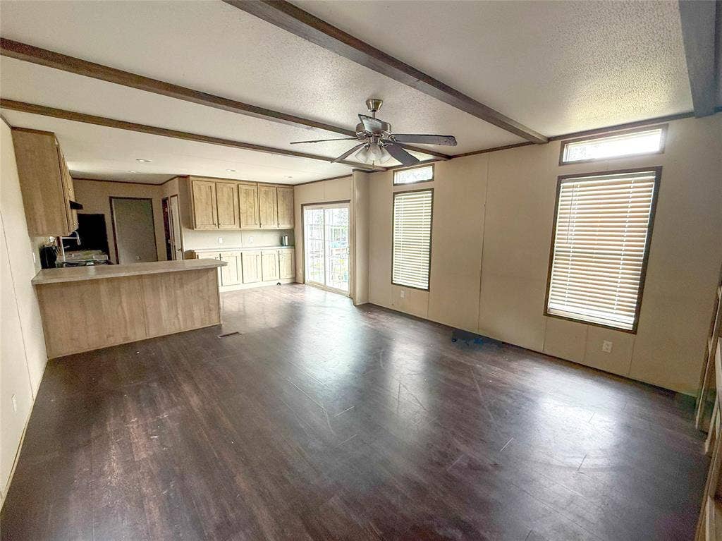 716 Quail Run Court, Seven Points, TX 75143 Open-concept living area featuring wood-finish flooring, exposed ceiling beams, and a ceiling fan