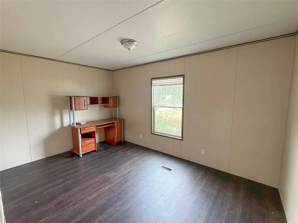 716 Quail Run Court, Seven Points, TX 75143 Spacious room featuring dark wood-finish flooring, neutral wall paneling, and a window with blinds
