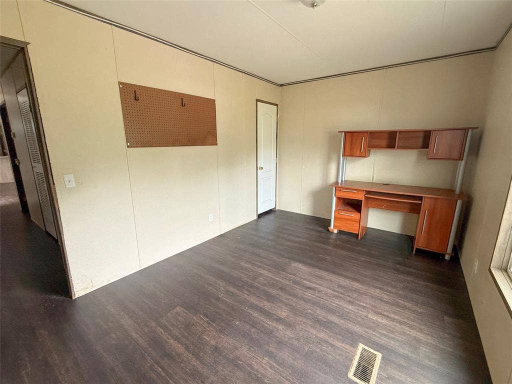 716 Quail Run Court, Seven Points, TX 75143 Spacious room featuring wood-finish flooring, light-toned panel walls, a built-in desk with shelving and cabinetry, and a white interior door