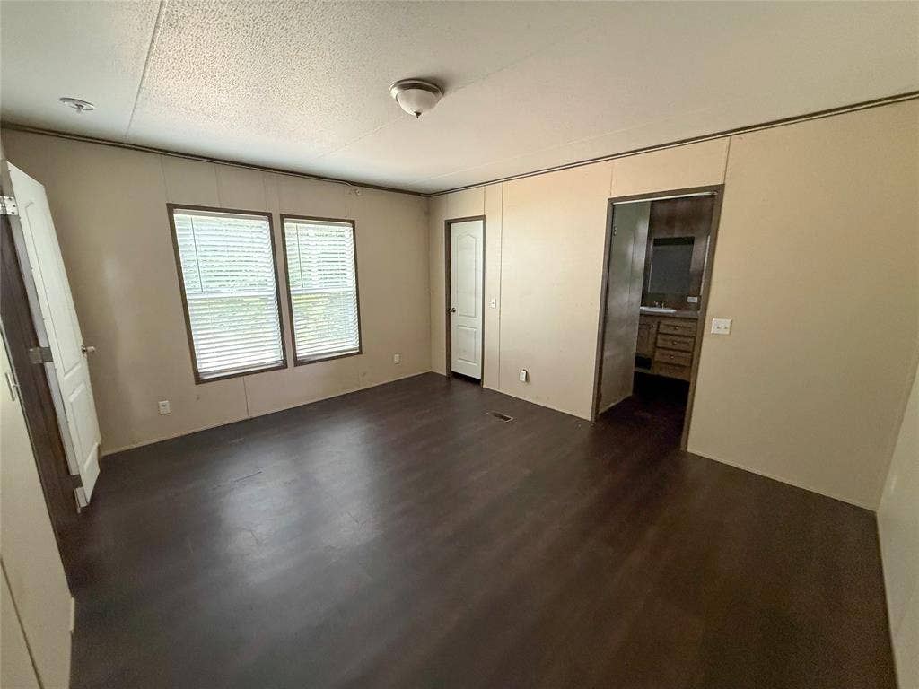 716 Quail Run Court, Seven Points, TX 75143 Spacious interior room featuring dark wood-finish flooring, neutral wall tones, and two windows with horizontal blinds