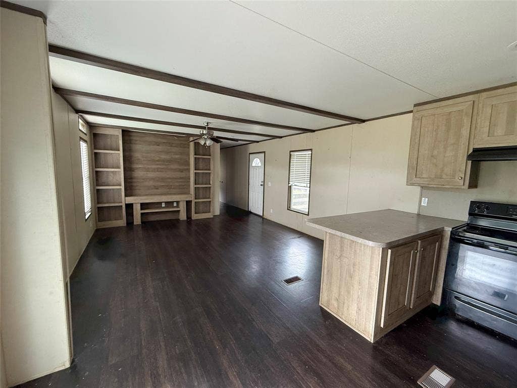 716 Quail Run Court, Seven Points, TX 75143 Open-concept living space with dark wood-finish flooring, exposed ceiling beams, and a built-in entertainment center featuring shelving and a wood-paneled accent wall
