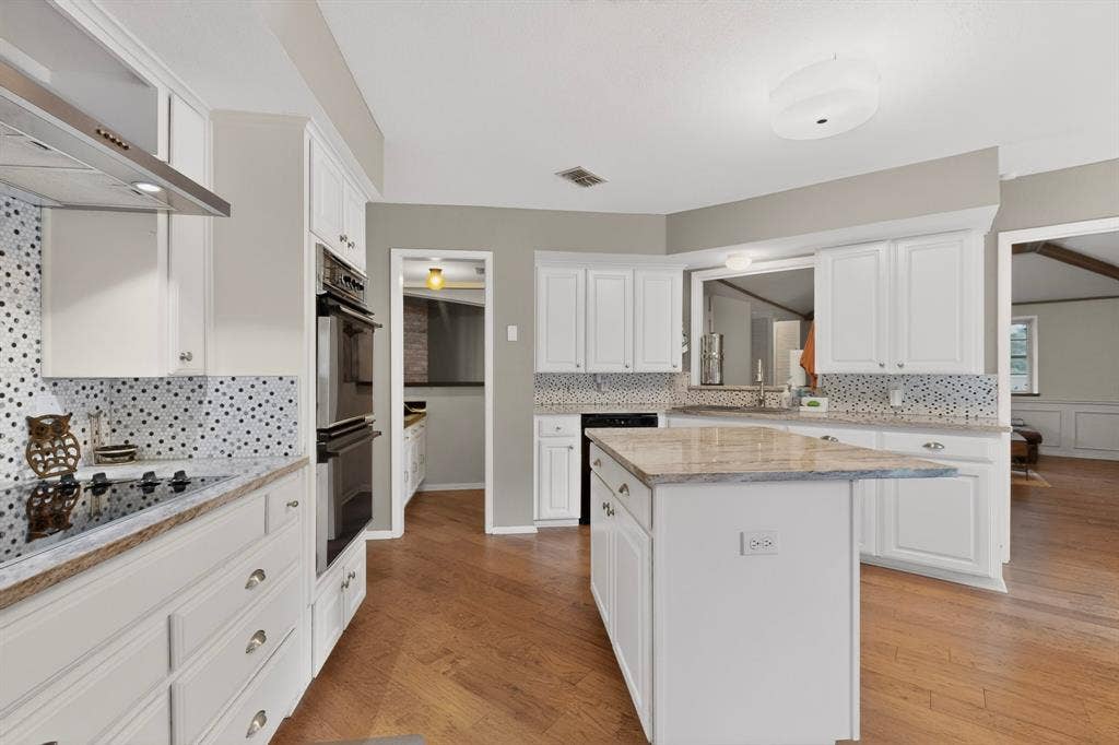 1151 Lynn Way, Waxahachie, TX 75165 Modern kitchen featuring white cabinetry, granite countertops, a built-in double oven, a smooth cooktop, and a mosaic tile backsplash