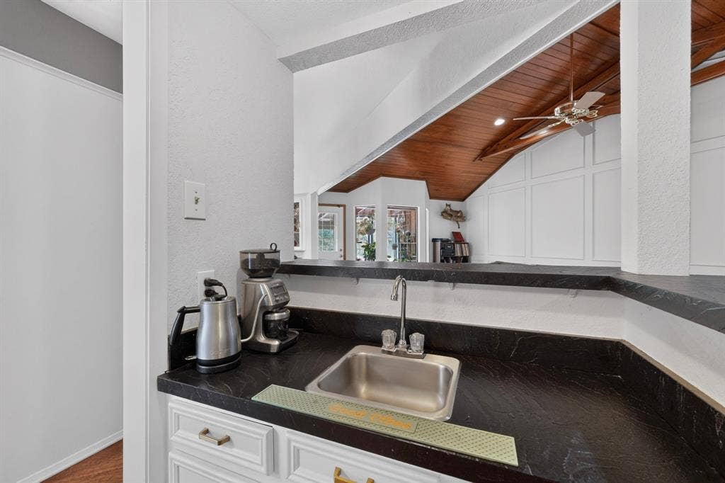 1151 Lynn Way, Waxahachie, TX 75165 Wet bar featuring a stainless steel sink, dark countertop, and white cabinetry