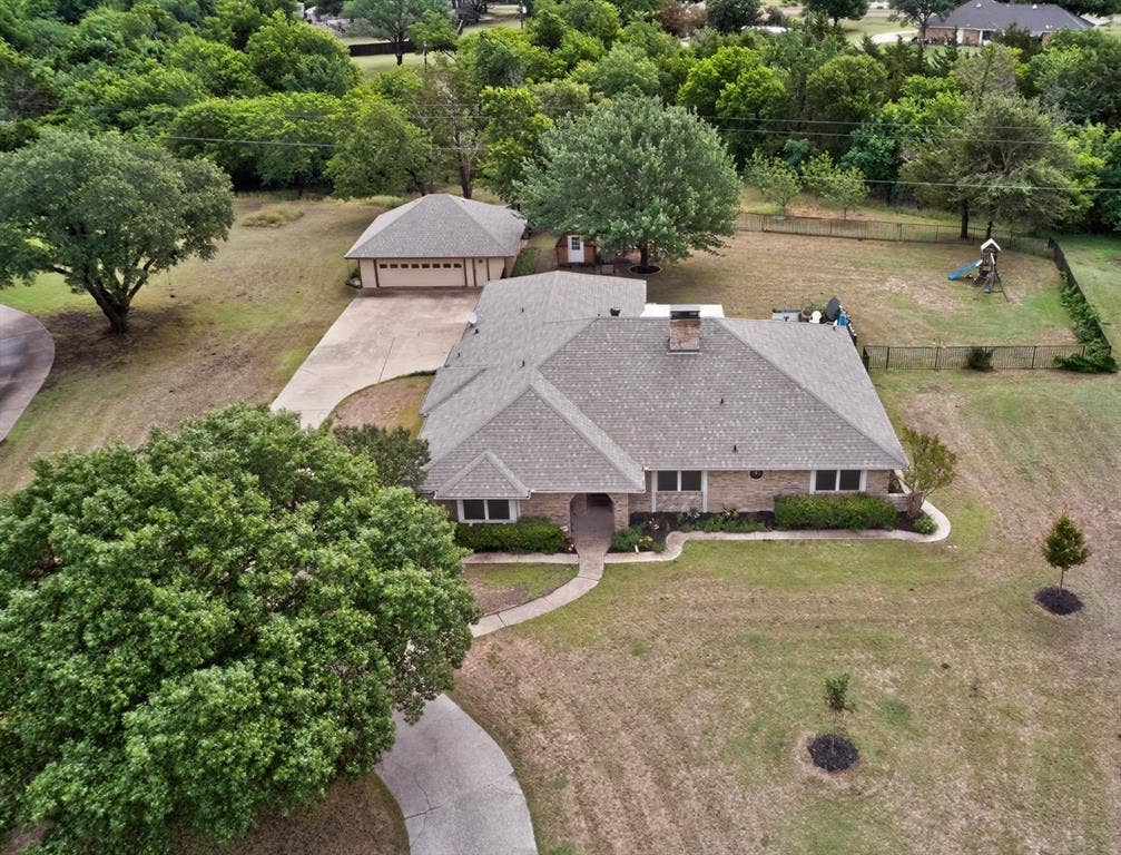 1151 Lynn Way, Waxahachie, TX 75165 Brick residence with a shingle roof, featuring a detached garage, concrete driveway, and established trees