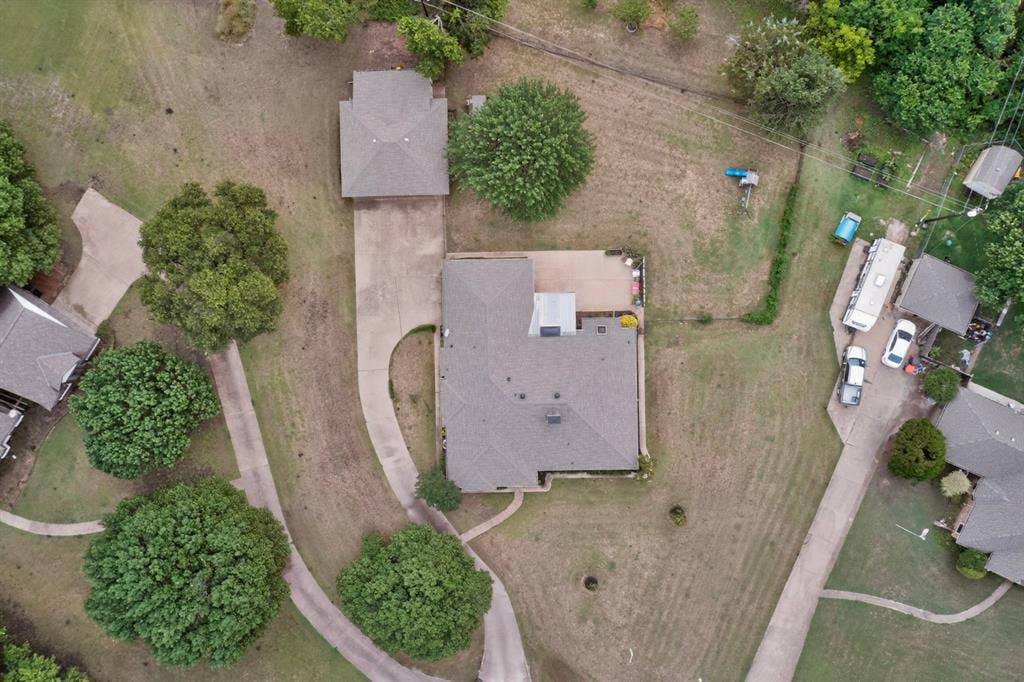 1151 Lynn Way, Waxahachie, TX 75165 Expansive property featuring a main residence with an additional detached structure, mature trees, and concrete driveways