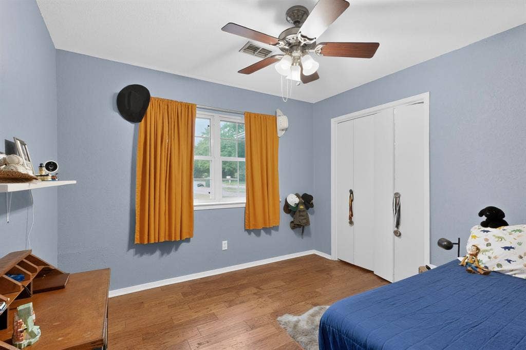 1151 Lynn Way, Waxahachie, TX 75165 Bedroom featuring wood-finish flooring, a ceiling fan with light fixture, and a window with white trim