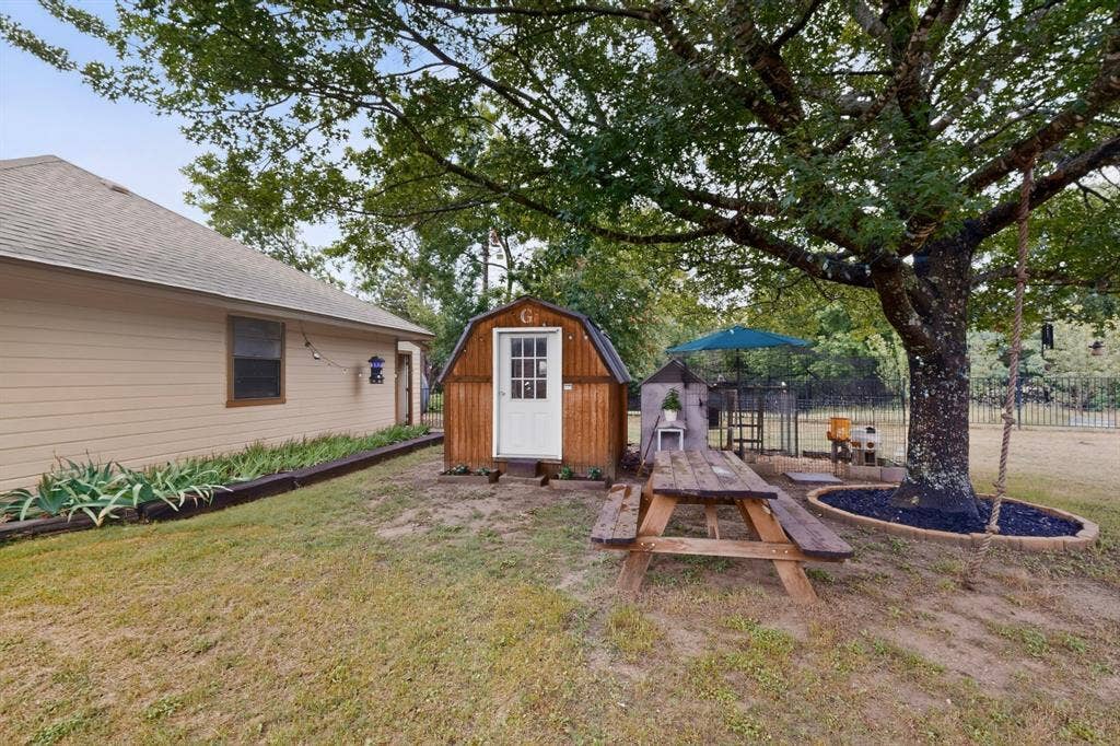 1151 Lynn Way, Waxahachie, TX 75165 Spacious backyard featuring a large tree with rope swing, a garden shed, and a picnic table
