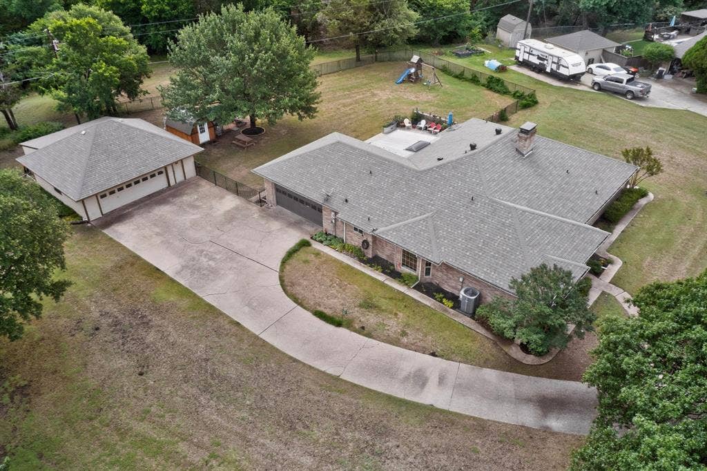 1151 Lynn Way, Waxahachie, TX 75165 Expansive property featuring a main residence with a multi-level roofline, a detached garage, a concrete driveway, a paved patio area, and mature landscaping