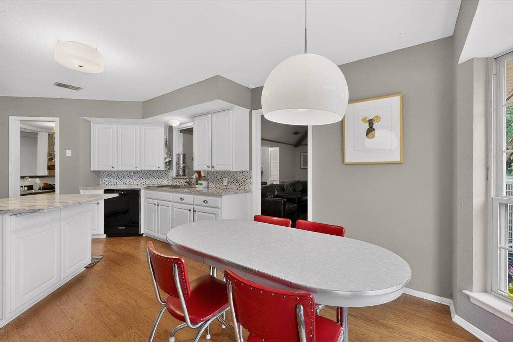 1151 Lynn Way, Waxahachie, TX 75165 Bright kitchen featuring white cabinetry, light-toned countertops, a mosaic tile backsplash, wood-finish flooring, and a contemporary pendant light fixture
