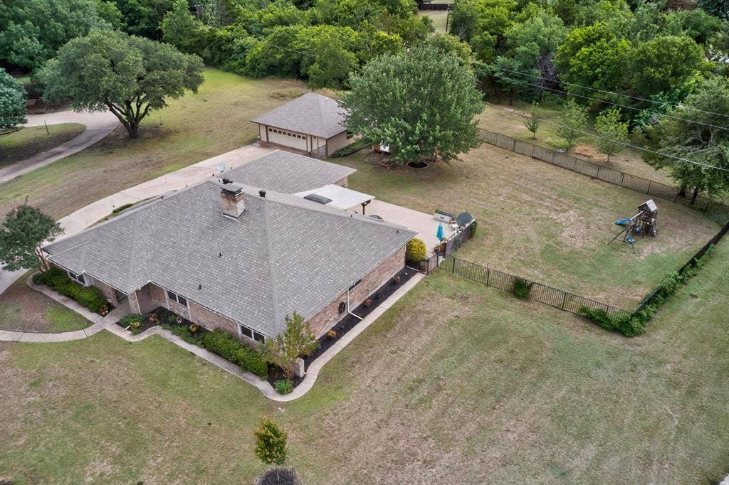 1151 Lynn Way, Waxahachie, TX 75165 Expansive property featuring a brick residence with a gray shingle roof, a detached garage with a matching roof, and a large fenced yard