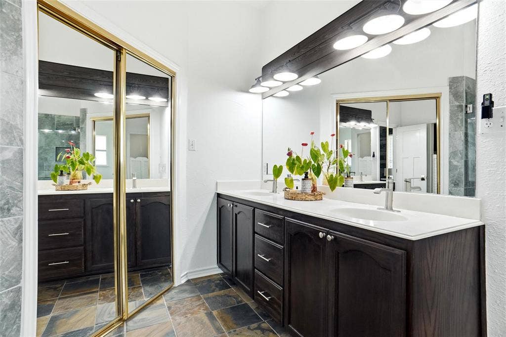 Dual vanity with white countertops, dual sinks, dark wood-finish cabinetry, and brushed nickel fixtures