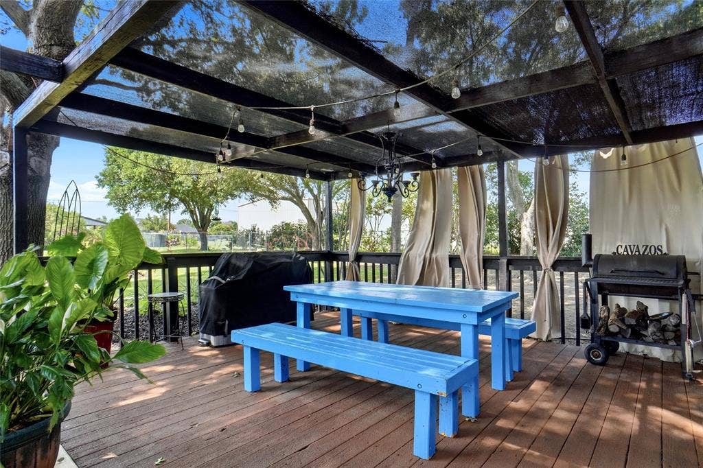 Expansive outdoor patio featuring wood-finish decking and a dark-stained wood pergola