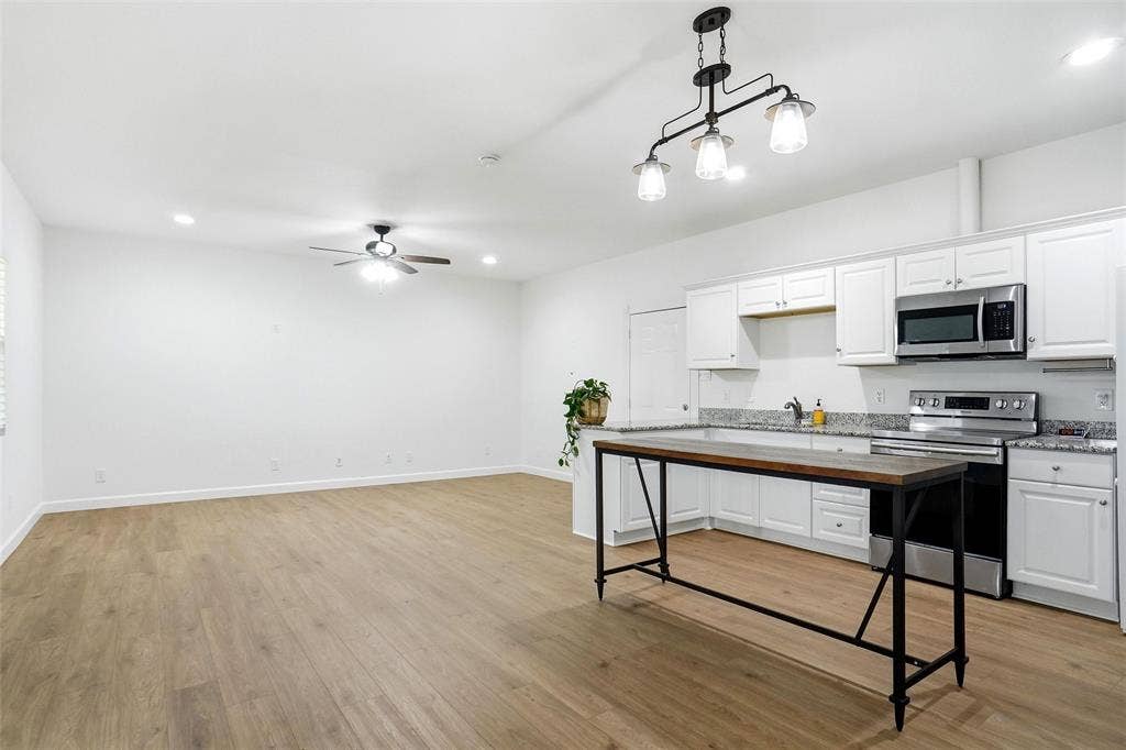 Open-concept living space featuring LVP wood-finish flooring, recessed lighting, and a ceiling fan