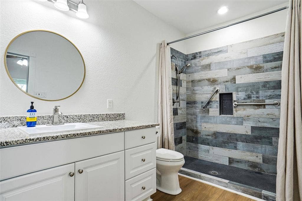 Bathroom featuring a white vanity with granite countertop, integrated sink, and brushed nickel faucet