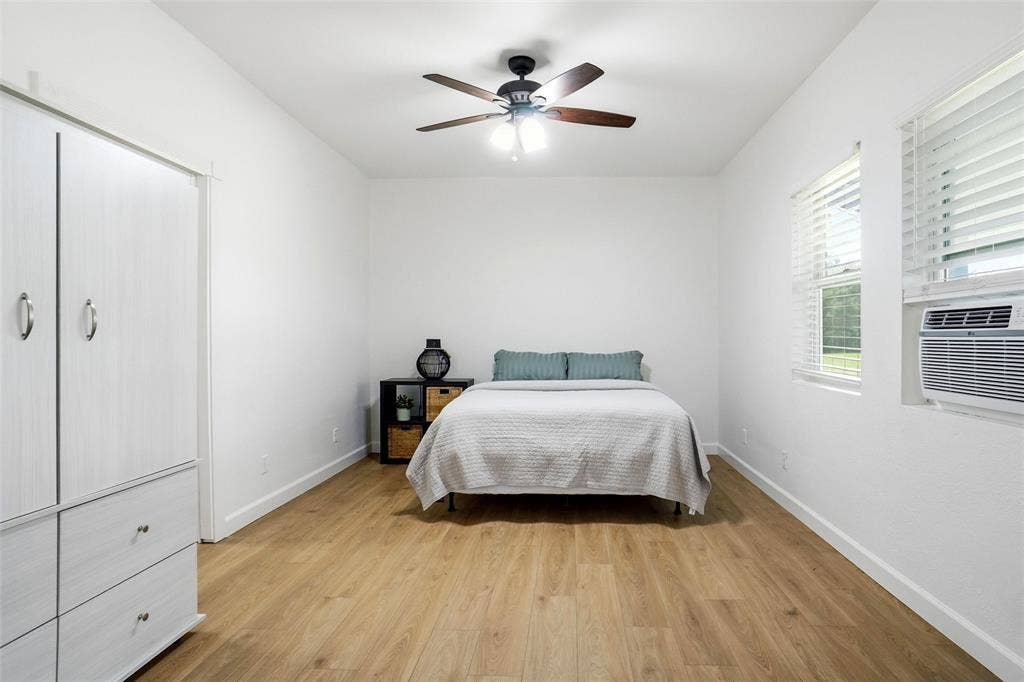 Bedroom featuring LVP wood-finish flooring, and a ceiling fan with integrated lighting