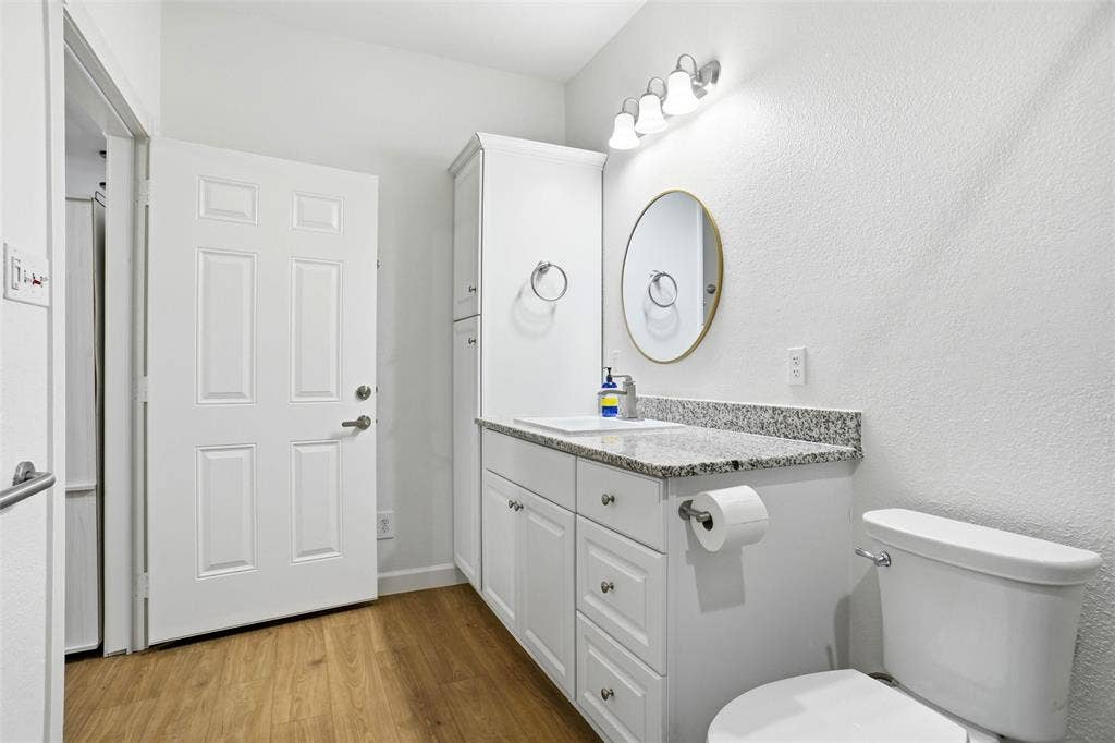Bathroom featuring a white vanity with granite countertop, single basin sink, and ample under-cabinet storage