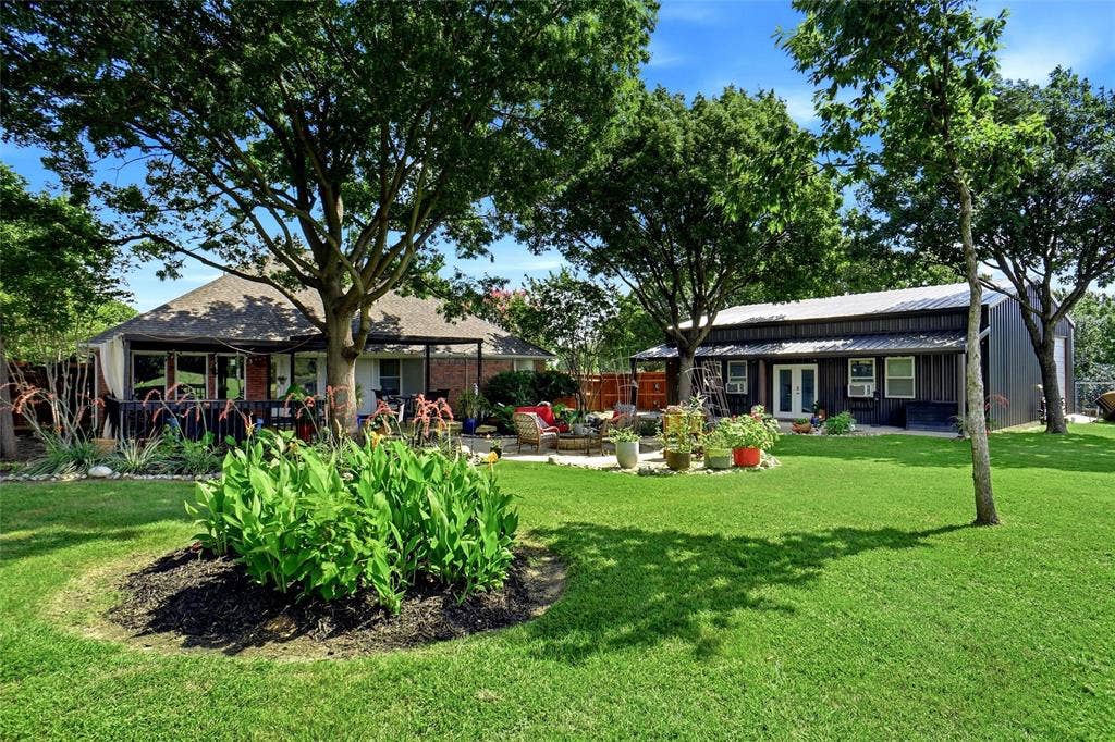 Expansive backyard with landscaping, mature trees, primary residence and barndominium