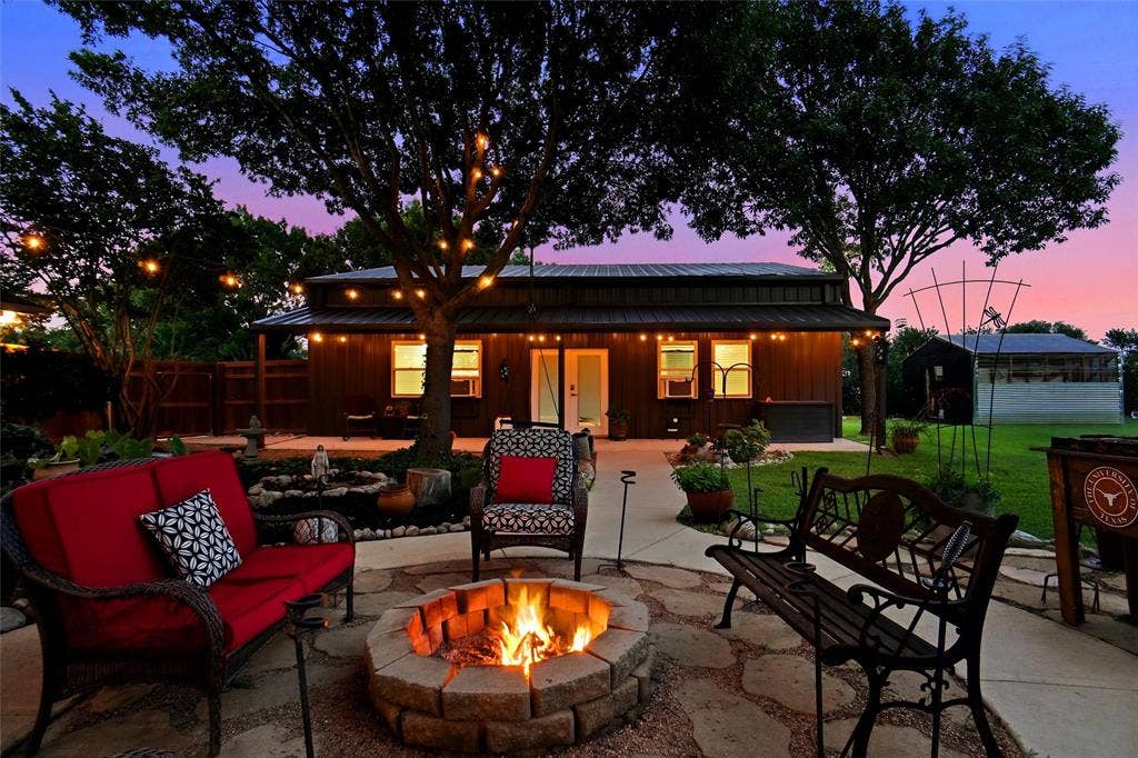 Backyard patio featuring a stone fire pit, flagstone pathway, and string lighting