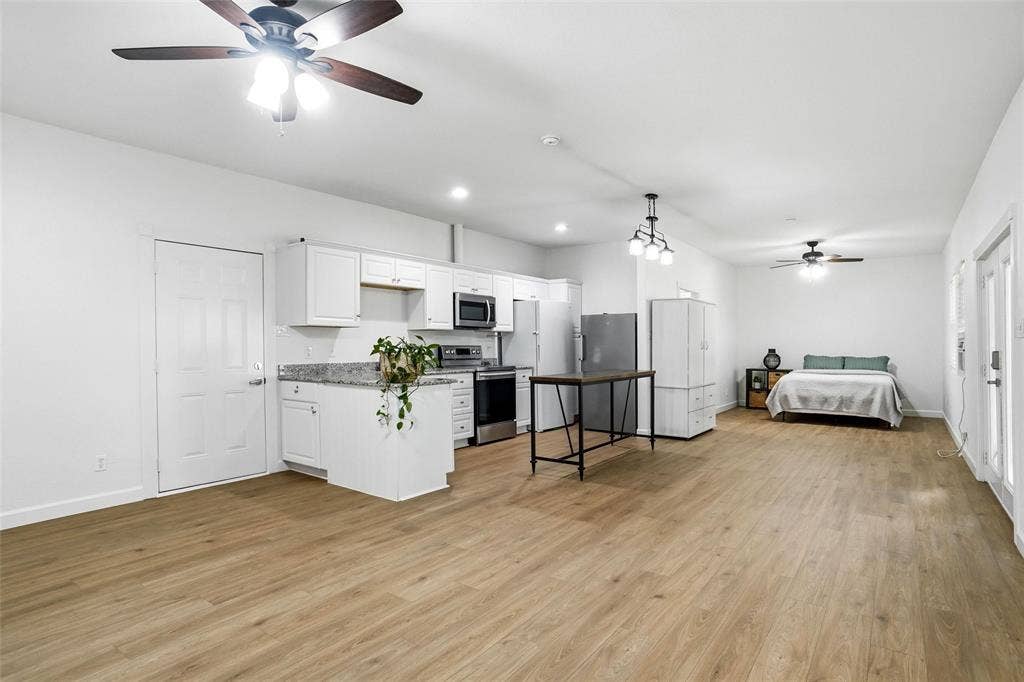 Open-concept living space and kitchen featuring LVP wood-finish flooring, recessed lighting, and a ceiling fan