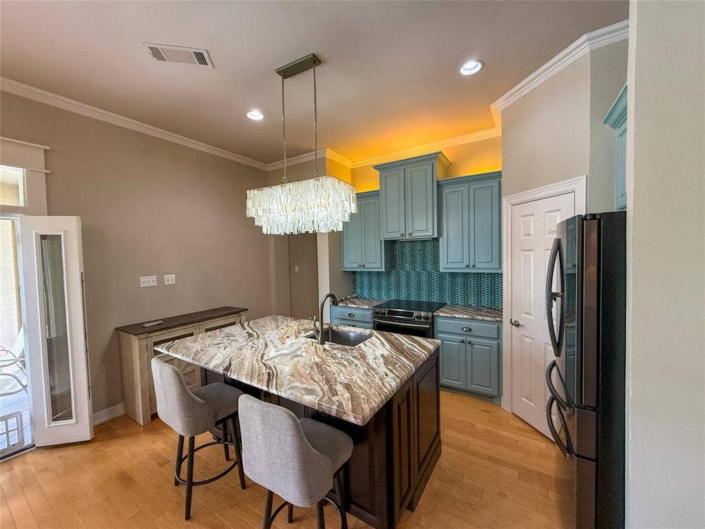 5 Woodlawn Way, Star Harbor, TX 75148 Kitchen island featuring a natural stone countertop, undermount sink, and integrated breakfast bar