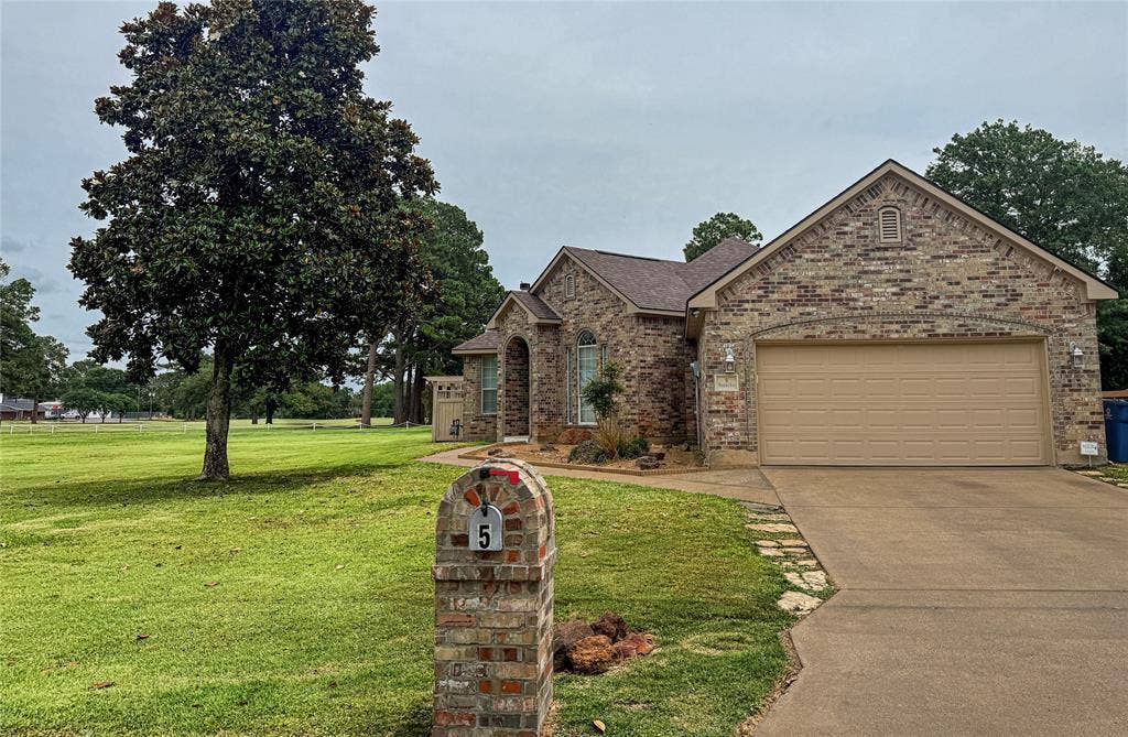 5 Woodlawn Way, Star Harbor, TX 75148 Brick exterior home featuring an attached two-car garage, concrete driveway, and an arched entry