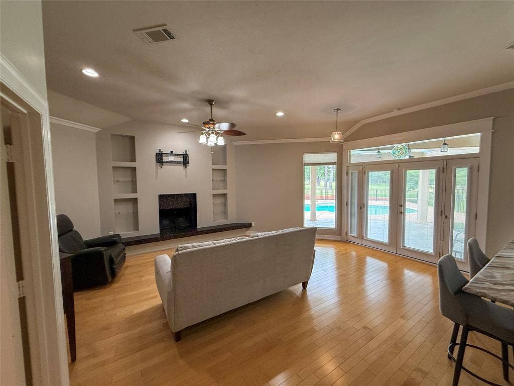 5 Woodlawn Way, Star Harbor, TX 75148 Spacious living area featuring wood-finish flooring, a fireplace with a dark stone surround, and built-in shelving