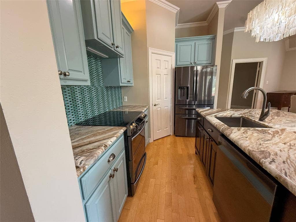 5 Woodlawn Way, Star Harbor, TX 75148 Kitchen featuring light blue cabinetry, patterned backsplash, wood-finish flooring, a kitchen island with an undermount sink and gooseneck faucet, and integrated stainless steel appliances