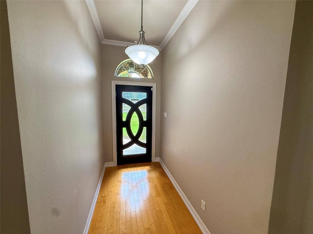 5 Woodlawn Way, Star Harbor, TX 75148 Entryway featuring a dark paneled door with decorative glass, an arched transom window, wood-finish flooring, and a pendant light fixture