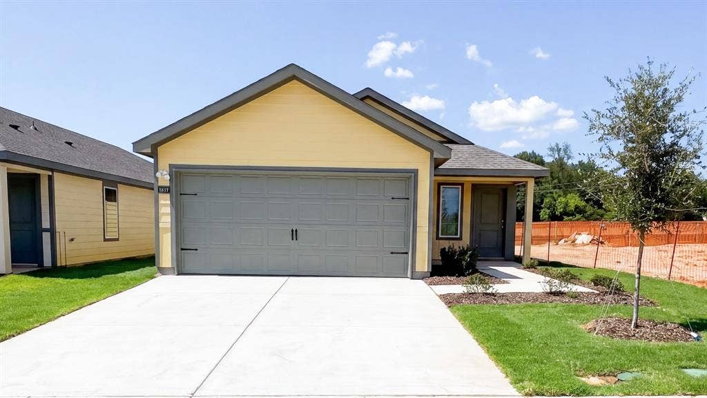1663 Blaire Drive, Tyler, TX 75702 Single-story residence featuring a two-car garage, covered entry, and a light yellow exterior with dark trim