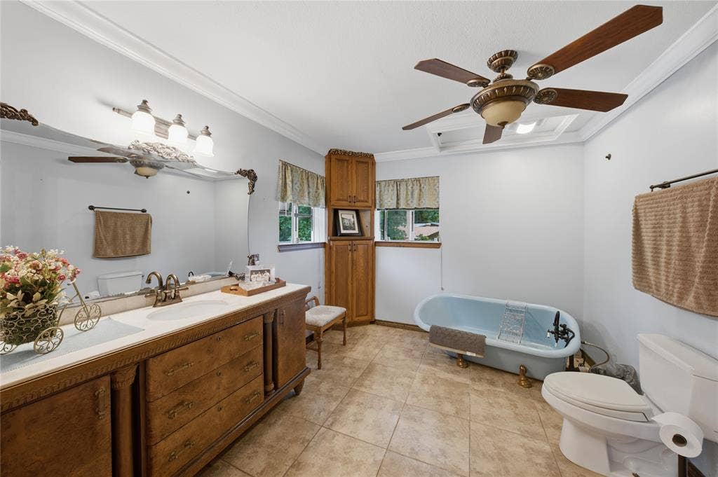 2746 Hopson Drive, Athens, TX 75752 Bathroom featuring a double vanity with an ornate wood-finish base and dual sinks, a clawfoot soaking tub, tile flooring, and a ceiling fan