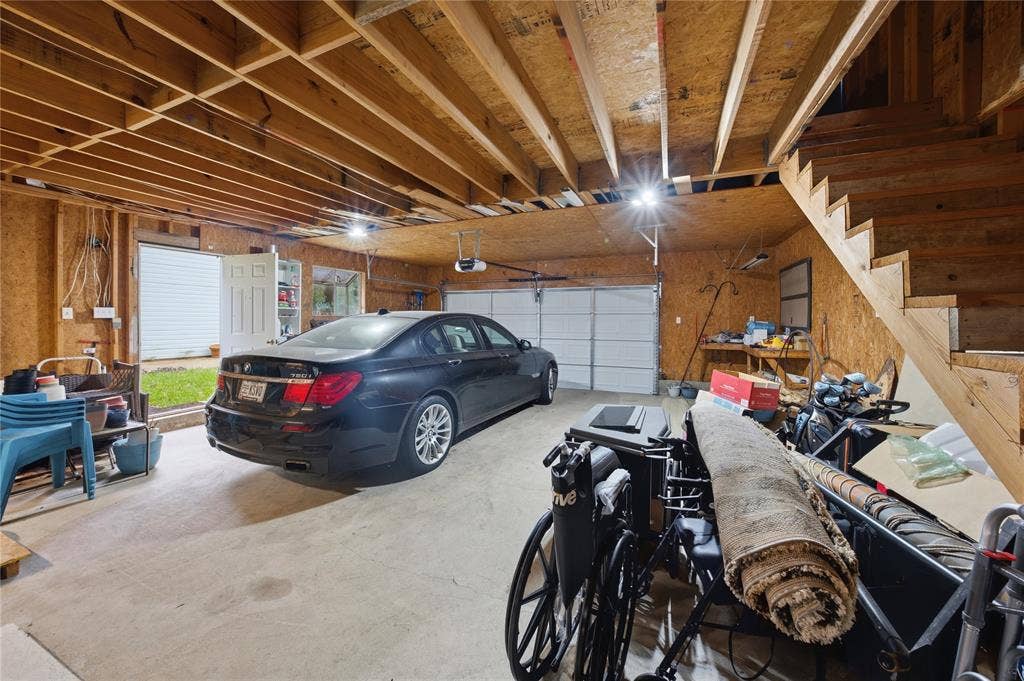 2746 Hopson Drive, Athens, TX 75752 Spacious garage with exposed wood framing, concrete flooring, dual overhead garage doors, and an interior access door