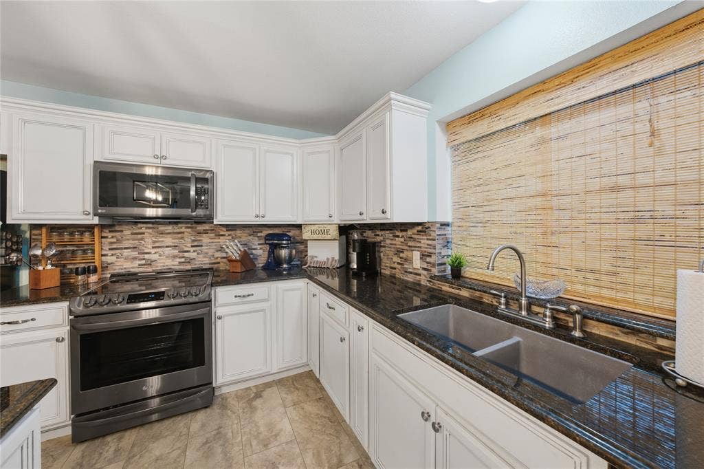 2746 Hopson Drive, Athens, TX 75752 Well-appointed kitchen featuring white cabinetry, dark stone countertops, and a mosaic tile backsplash