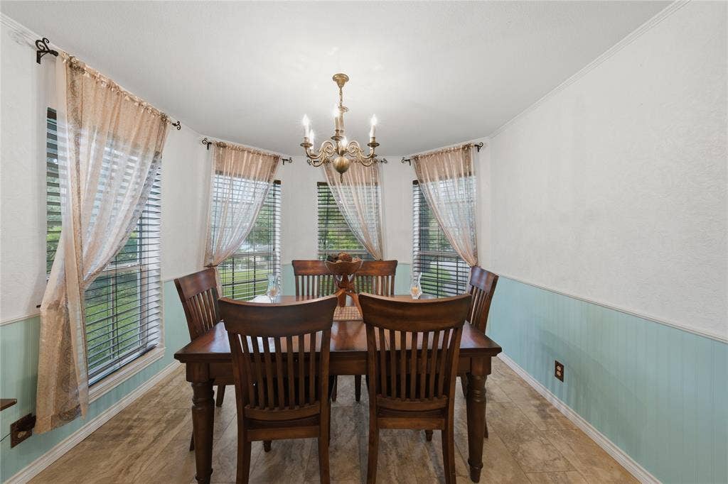 2746 Hopson Drive, Athens, TX 75752 Dining area featuring a classic chandelier, paneled wainscoting, decorative wall texture, and multiple windows with blinds
