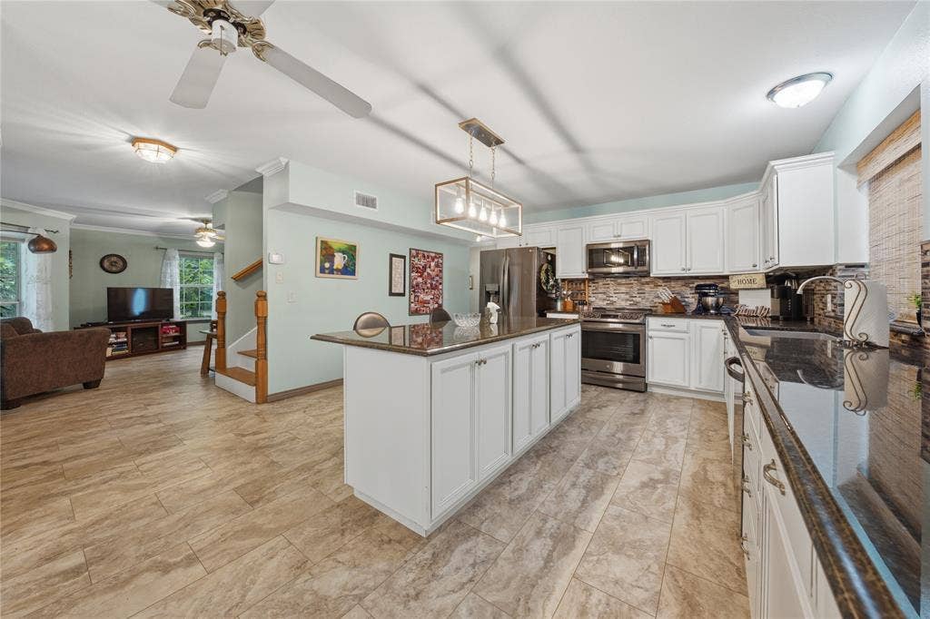 2746 Hopson Drive, Athens, TX 75752 Kitchen featuring white cabinetry, dark countertops, stainless steel appliances, and a central island with storage