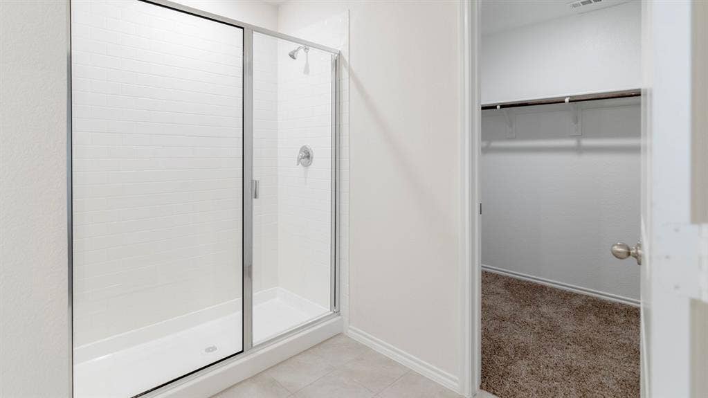 1627 Blaire Drive, Tyler, TX 75702 Shower enclosure with clear glass door, white subway tile surround, chrome fixtures, and a white shower pan