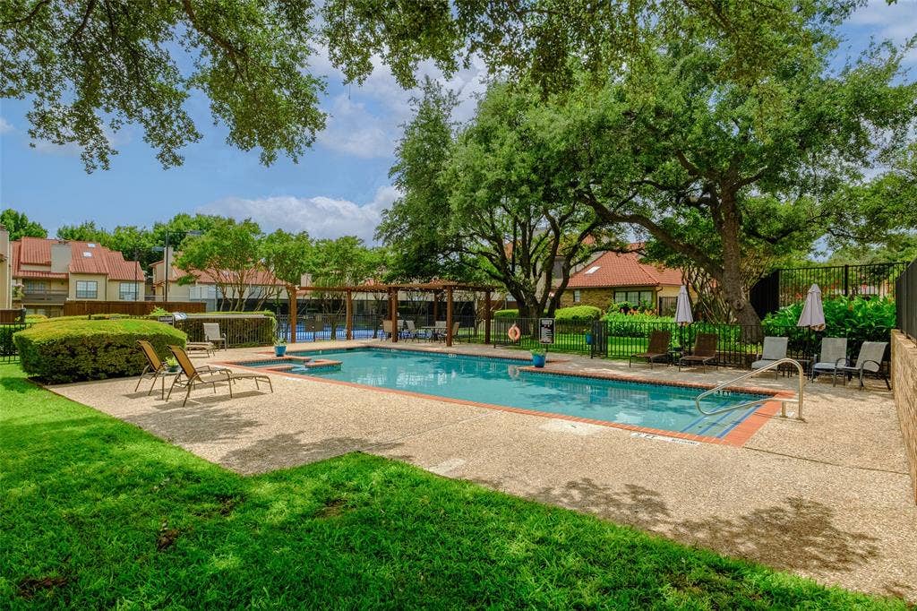4130 Proton Drive, #47B, Addison, TX 75001 Lush, tree-shaded view of the community pool and sun deck with lounge seating, a pergola-covered gathering area, and the La Mirada roofline as a backdrop — the definition of low-maintenance resort living.