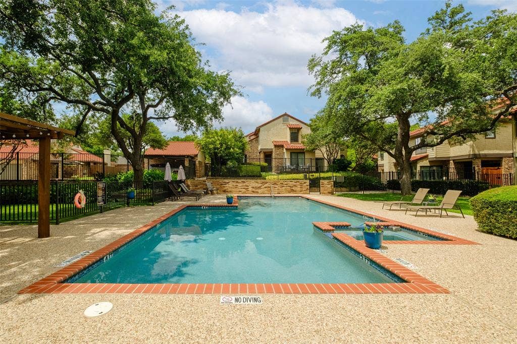 4130 Proton Drive, #47B, Addison, TX 75001 Resort-style community pool with brick coping, spa, lounge chairs, pergola, and mature live oak canopy — a peaceful escape steps from your front door.