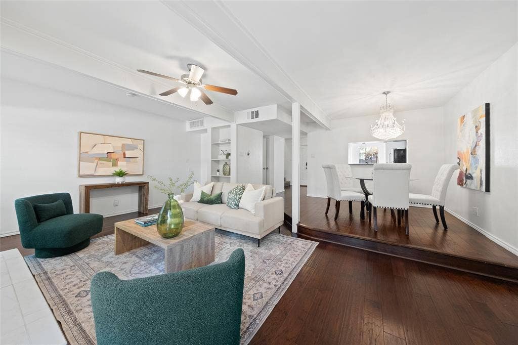 4130 Proton Drive, #47B, Addison, TX 75001 Open-concept main level connecting the living room and dining area, with continuous hardwood floors, a crystal chandelier anchoring the dining space, and views straight through to the kitchen.
