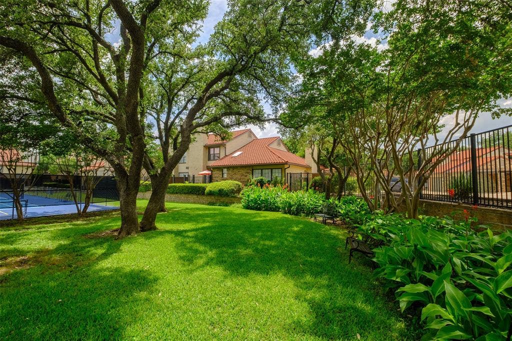 4130 Proton Drive, #47B, Addison, TX 75001 Beautifully landscaped community common area with sweeping lawn, mature live oaks, colorful flowering beds, and a tucked-away bench