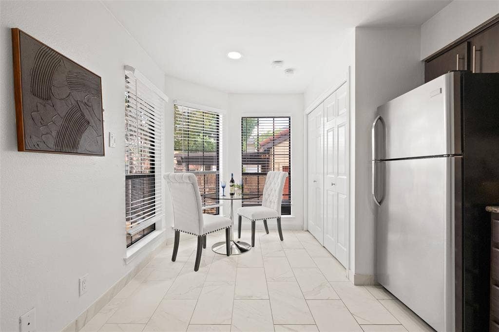 4130 Proton Drive, #47B, Addison, TX 75001 Bright breakfast nook with large windows, marble-look tile flooring, and a cozy two-seat café table — the perfect morning coffee spot with natural light on all sides.