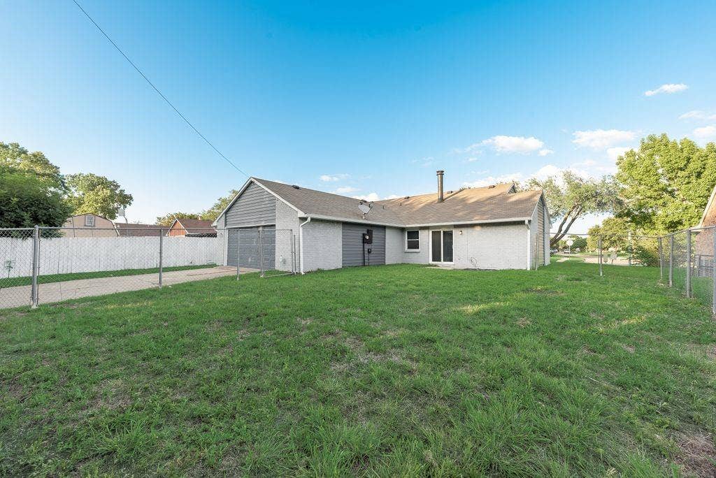 316 Matterhorn Street, Cedar Hill, TX 75104 Rear exterior featuring a two-car garage with shingle siding, a patio door, and a partially fenced yard