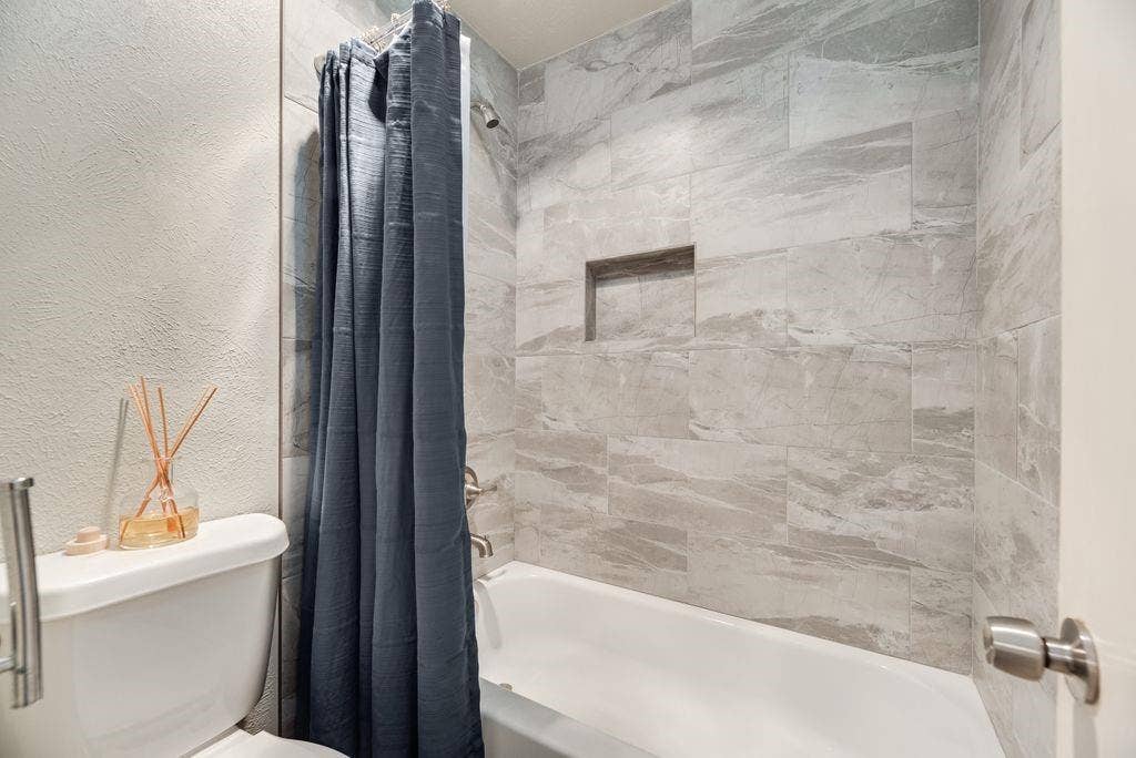 316 Matterhorn Street, Cedar Hill, TX 75104 Bathtub and shower combination featuring large format grey tile surround, recessed shower niche, and brushed nickel fixtures
