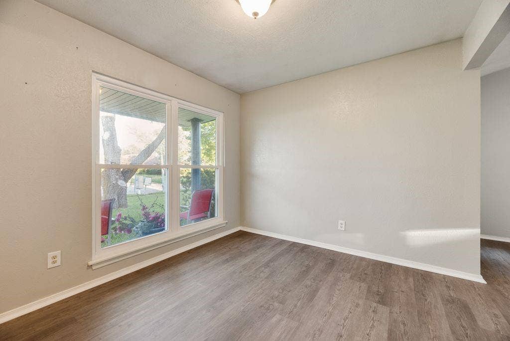 316 Matterhorn Street, Cedar Hill, TX 75104 Neutral wall paint, wood-finish flooring, white baseboards, and a double window looking out to the yard