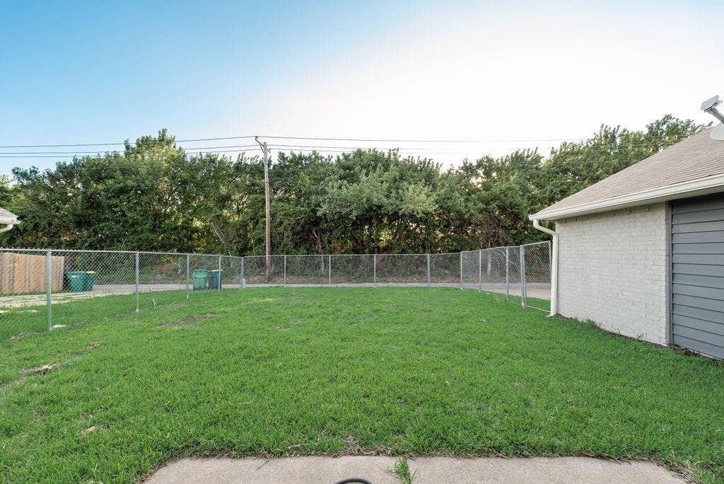 316 Matterhorn Street, Cedar Hill, TX 75104 Expansive fenced yard featuring a concrete patio, green lawn, and chain-link perimeter