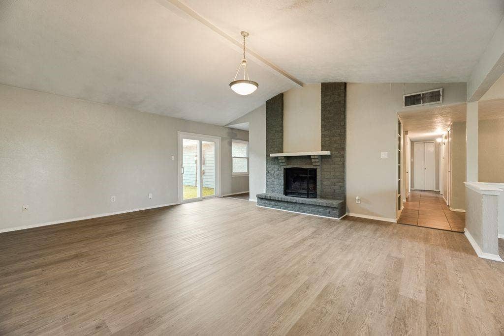 316 Matterhorn Street, Cedar Hill, TX 75104 Spacious living area featuring wood-finish flooring, a brick fireplace with a mantle, and vaulted ceilings